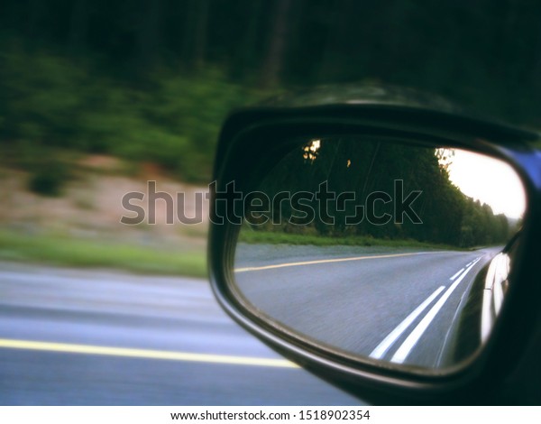 View of road in the side rear-view mirror of car\
at speed in motion