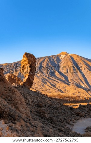View of rock formations Roques de Garcia or Roque Cinchado and Teide mountain volcano at sunset, Teide National Park, Tenerife, Spain. Golden hour.