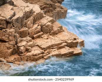 View of rocky coastline with waves crashing against the rocks. The scene features textured rocks, surrounded by clear turquoise water. - Powered by Shutterstock