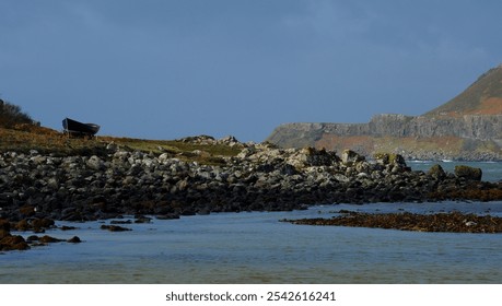 view of a rocky sea shore with small boat on the beach - Powered by Shutterstock