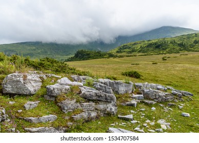 View from Rodnei mountains in Romania with rocks in the foreground and forested hills with low clouds in the background