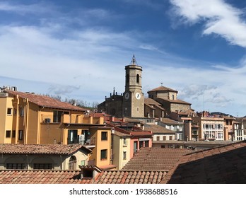 View from the rooftops of Olot, with its buildings and the Church of Sant Esteve in the center. With a sky with fine clouds and clear blue. Sunny day. Vivid and colored tones of its rehabilitated buil