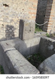 View Of The Ruins Of A Water Fountain With A Face Sculpture Located In Pompeii, Italy