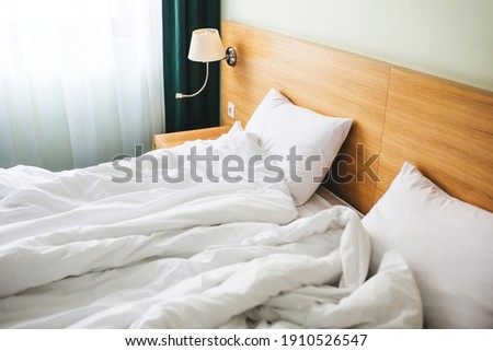 View of a rumpled bed with white pillows and a duvet.