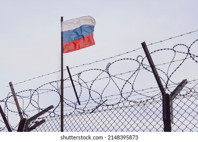 View of russian flag behind barbed wire against cloudy sky. Concept anti-Russian sanctions. A border post on the border of Russia. cancel culture Russia in the world - Shutterstock ID 2148395873