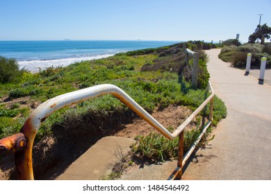 View Of The Rusted White Painted Metal Pipe Fence Near The Storm Water Drain At Ocean Beach, Bunbury, Western Australia In Late Winter.