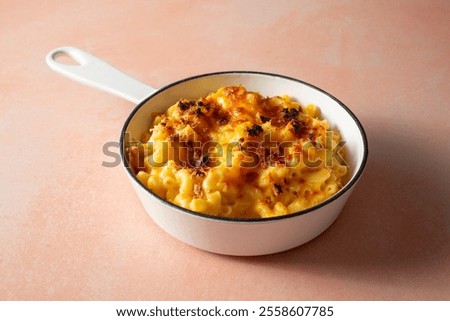 A view of a rustic mac n cheese entree in an enameled cast iron skillet.