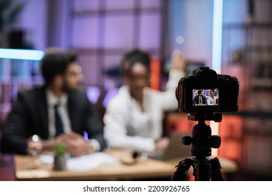 View From Screen Of Camera With Attractive Male And Female Financiers, Arab Manager And Confident African American Business Woman Explaining Online Economic Charts On Glass Board To Their Colleagues.