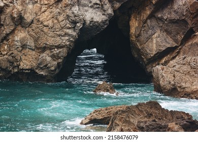 The View Of The Sea Cave Entrance With Rocks On The Turquoise Water Surface 