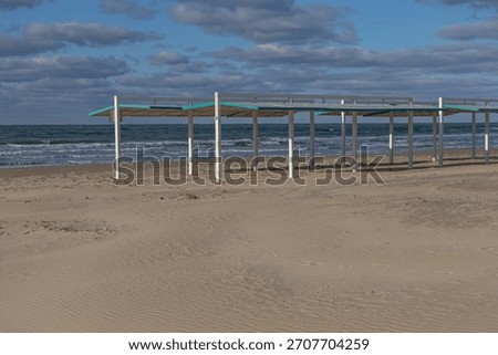 View of the sea and clouds in winter. Waves on the sea turning into a blue sky with clouds. Winter sea during a storm. A sandy beach by the sea in the off-season.