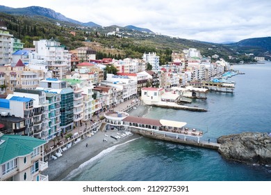 View from the sea on the embankment of the resort village of Utes in the Crimea with colorful facades of buildings. All-season period. Shooting from a drone.