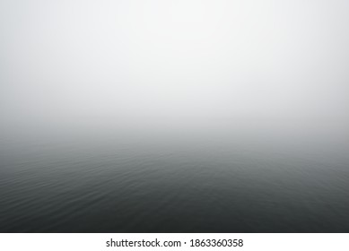 A view of the sea. Thick fog. Symmetry reflections on the water. Natural mirror. Dark atmospheric landscape. Abstract art, texture, background, wallpaper, grey color, monochrome, black and white - Powered by Shutterstock