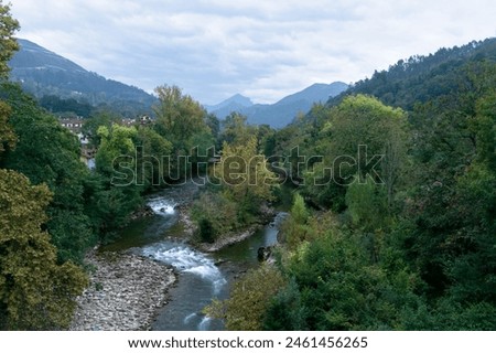 View of the Sella River passing through Cangas de Onis surrounded by dense vegetation and a beautiful mountain landscape. Cangas de Onis - Asturias