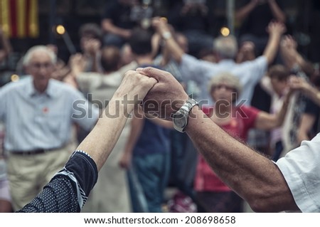 View of senior people holding hands and dancing national dance Sardana at Plaza Nova, Barcelona, Spain. It is a type of circle dance typical of Catalonia.