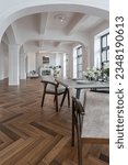 a view of a set dining table in a chic expensive bright interior of a huge living room in a historic mansion with arched arches, columns and white walls decorated with ornaments and stucco.