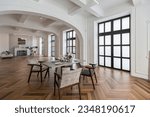 a view of a set dining table in a chic expensive bright interior of a huge living room in a historic mansion with arched arches, columns and white walls decorated with ornaments and stucco.