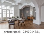 a view of a set dining table in a chic expensive bright interior of a huge living room in a historic mansion with arched arches, columns and white walls decorated with ornaments and stucco.