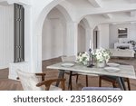 a view of a set dining table in a chic expensive bright interior of a huge living room in a historic mansion with arched arches, columns and white walls decorated with ornaments and stucco.
