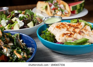 A view of several Californian Mediterranean fusion dishes on a table, featuring chicken and salads.