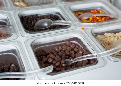 A View Of Several Containers Full Of Toppings In A Frozen Yogurt Or Ice Cream Shop Setting.