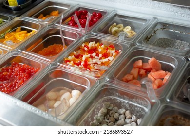 A View Of Several Containers Full Of Toppings In A Frozen Yogurt Or Ice Cream Shop Setting.