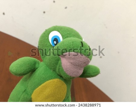 The view from several viewing angles of a baby dinosaur doll is not clear what species it is, which has the characteristics, mostly green, thick pink lips, blue eyes and yellow belly and legs