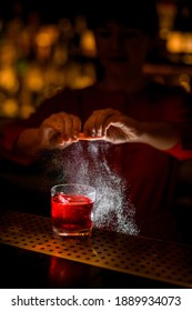 View Of Shiny Old Fashioned Glass With Drink On Bar, On Which Hands Of Woman Bartender Neatly Sprinkles Juice Of Citrus Zest