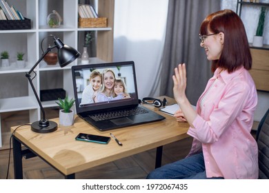 View From Shoulder Of Woman Talking With Her Family Through Video Call. Young Female Staying At Home And Using Modern Laptop For Distance Communication.