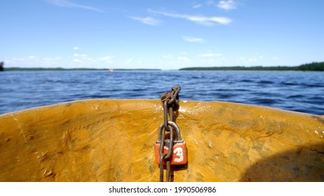 View From The Side Of The Boat. Sailing About A Blue Lake On A Sunny Day Past An Island With A Green Forest. Clear Sky Reflecting From Smooth Water. 