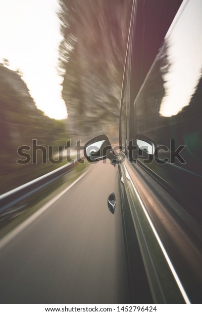 View from side of Car moving in a mountaint\
blurred road with metal\
fence.
