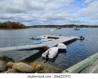 The View From The Side Of A Dock. There Are Multiple Row Boats And Inflated Motor Boats Tied To The Tiny Dock.