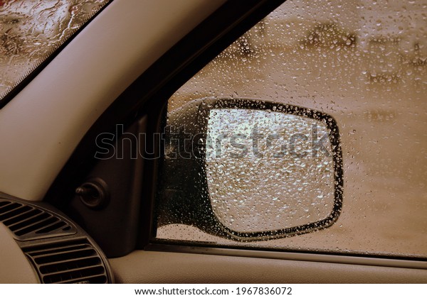 view in the side mirror from the inside of the car\
with rain on the glass