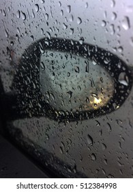 View side mirror with rain drop on the road and car headlights