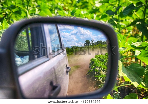 View in the\
side mirror when driving a crossover at a high speed on a\
picturesque dusty field road in the\
summer