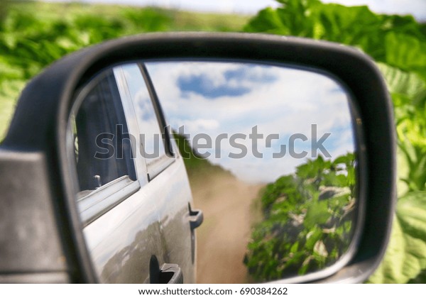 View in the\
side mirror when driving a crossover at a high speed on a\
picturesque dusty field road in the\
summer