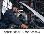 View from the side, opened hood. Mechanic working in a car service station.