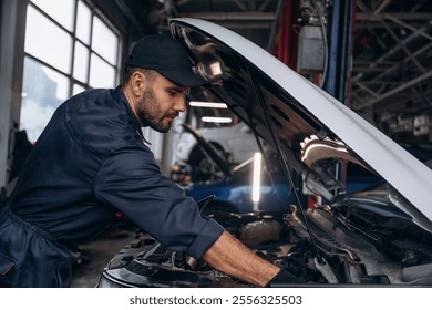 View from the side, opened hood. Mechanic working in a car service station.