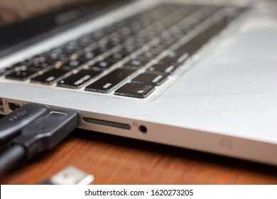 A view of the side panel and port outlets area of a laptop computer on a wooden desk.