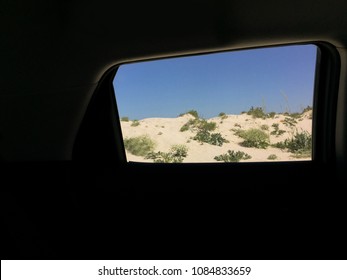 View From The Side Window Of The Car On Beautiful Seascape With Sand, Shells And Wild Sea Flowers, Tumbleweed/ Summer Beach Vacation Background