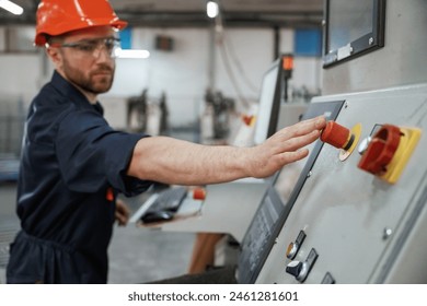 View from the side, working with machine, operator. Factory worker is indoors with hard hat. - Powered by Shutterstock