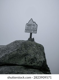 View of a sign marking the elevation at Whiteface Mountain. A sign shows the height of 4867 feet above sea level at Whiteface Mountain in cloudy weather.