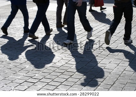 View of silhouetted people crossing road in city center