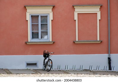 A View Of A Single Tourist Bike Standing Next To A Bike Parking Spot Located Next To An Old Yet Renovated Building And A Square Covered With Stones And Boulders Spotted In A Polish Village In Summer