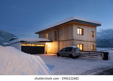 View Of Single-family House With Garage In Snow-covered Winter With Cleared Entrance At Night