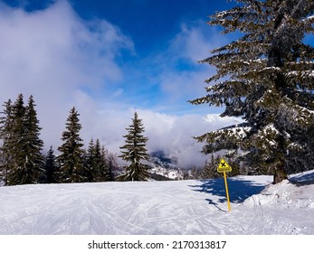 View of ski track with crossing yellow sign on it over high altitude clouds in the mountains