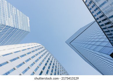 The view of the sky between three skyscrapers. Modern office buildings in the financial district. Glass towers in downtown of the city. A cluster of tall buildings.