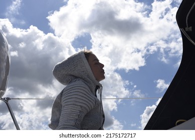 The View To The Sky. A View Of The Sky Full Of Beautiful Little Clouds On The Move. A Woman's Profile With A Hood On Her Head. A Stylishly Futuristic Dressed Girl On A Boat.