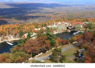 View from Skytop looking down on Mohonk Lake and Mohonk Mountain House resort surrounded by sandstone cliffs and colorful Autumn trees in the Shawangunk Mountains of New York