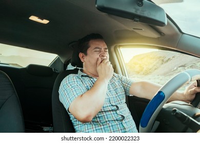 View Of A Sleepy Driver In His Car. Tired Driver Yawning In The Car, Concept Of Man Yawning While Driving. A Sleepy Driver At The Wheel, A Tired Person While Driving