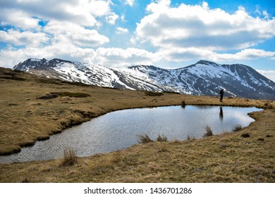 View of small mountain lake in spring and silhouette of lonely hiker 